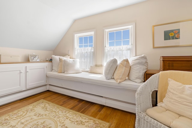bedroom with a baseboard radiator, wood finished floors, and lofted ceiling