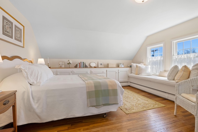 bedroom featuring light wood-type flooring, baseboard heating, and vaulted ceiling