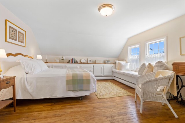 bedroom with light wood-style flooring, lofted ceiling, and baseboard heating