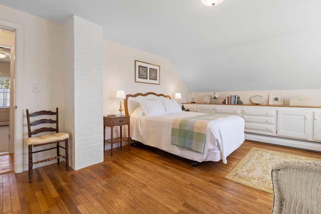 bedroom featuring baseboards, a baseboard radiator, vaulted ceiling, and hardwood / wood-style floors