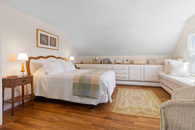bedroom with wood finished floors and lofted ceiling