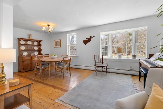 dining area with an inviting chandelier, a baseboard radiator, and light wood-type flooring