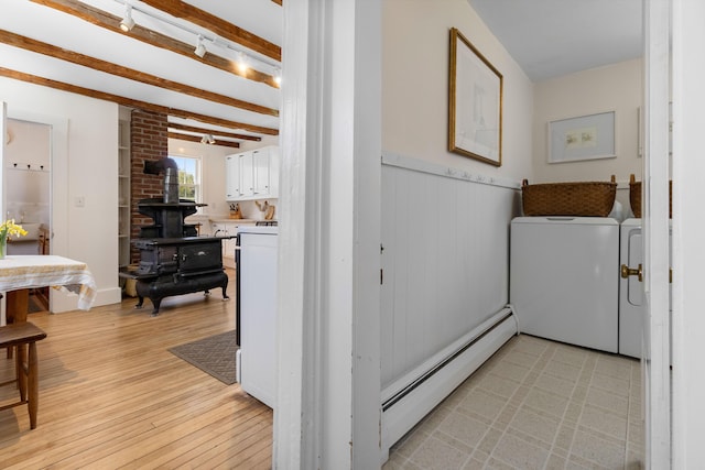 corridor featuring wainscoting, beam ceiling, a baseboard heating unit, light wood finished floors, and separate washer and dryer