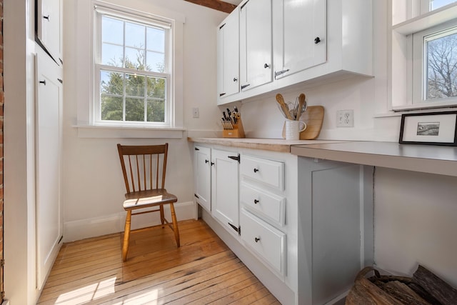 interior space with light countertops, light wood-style flooring, a wealth of natural light, and white cabinets