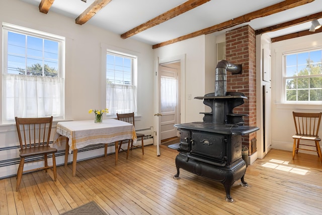 living area featuring a wood stove, light wood finished floors, and beam ceiling