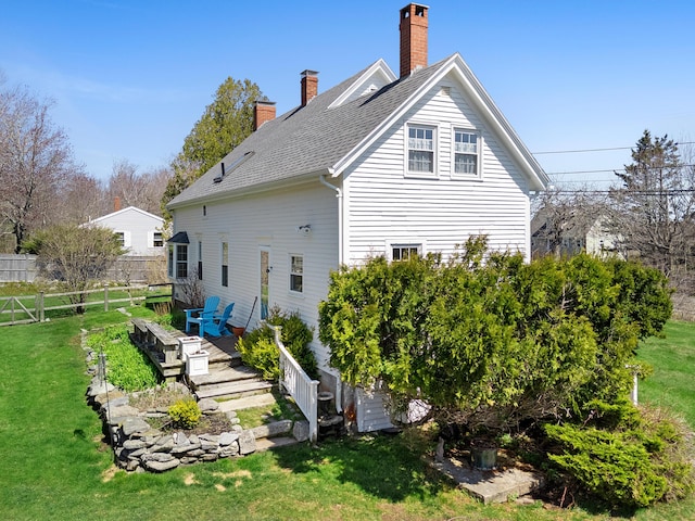 rear view of house featuring fence, a chimney, a lawn, and a deck