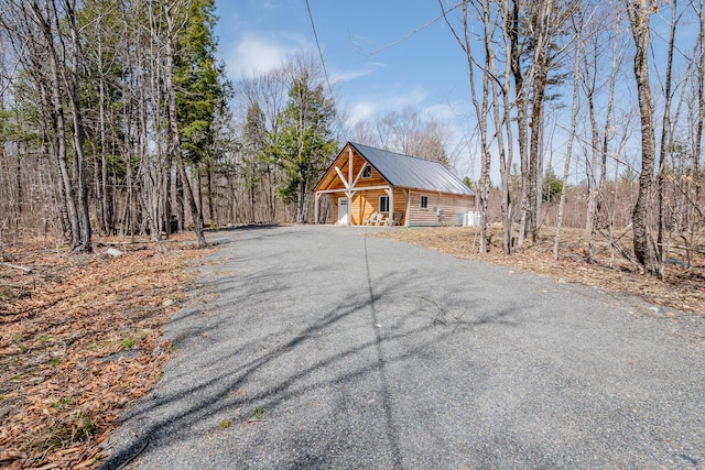 view of front of home featuring aphalt driveway, covered porch, and metal roof