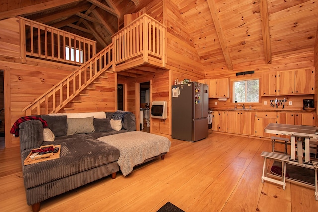living room featuring stairway, high vaulted ceiling, wood walls, and beam ceiling