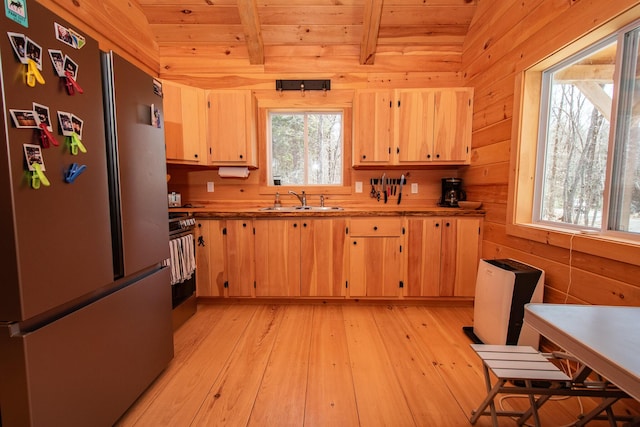 kitchen featuring light brown cabinetry, beam ceiling, a sink, freestanding refrigerator, and wood ceiling
