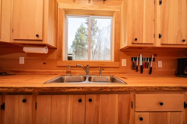kitchen with a sink, light brown cabinets, and wood counters