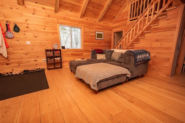 living area featuring wooden ceiling, lofted ceiling with beams, light wood finished floors, wooden walls, and stairs