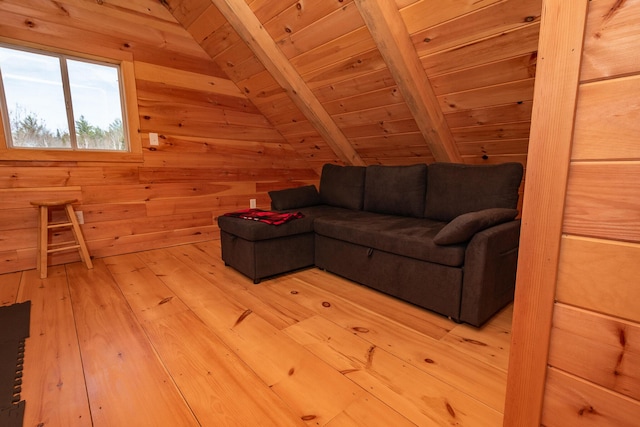 living area with lofted ceiling with beams, wood ceiling, wooden walls, and light wood-style flooring