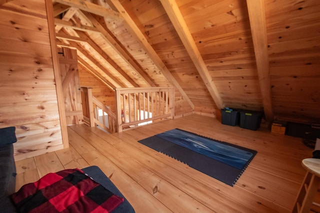 additional living space with lofted ceiling with beams, wooden walls, wooden ceiling, and hardwood / wood-style flooring