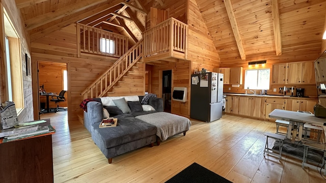 living room featuring light wood-style floors, high vaulted ceiling, wood walls, stairs, and wood ceiling