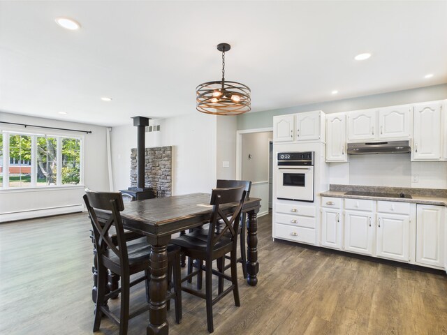 80 Garden Cir, Caribou, ME 04736 - dining room with baseboard heating, dark wood-style floors, a wood stove, a chandelier, and recessed lighting