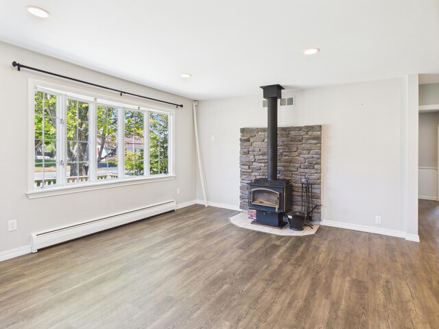 80 Garden Cir, Caribou, ME 04736 - unfurnished living room featuring baseboard heating, a wood stove, wood finished floors, baseboards, and recessed lighting