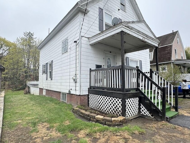 rear view of property featuring a yard and a wooden deck