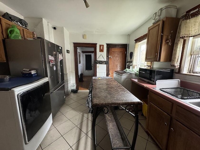 kitchen featuring plenty of natural light, washer / clothes dryer, light tile patterned flooring, and black microwave