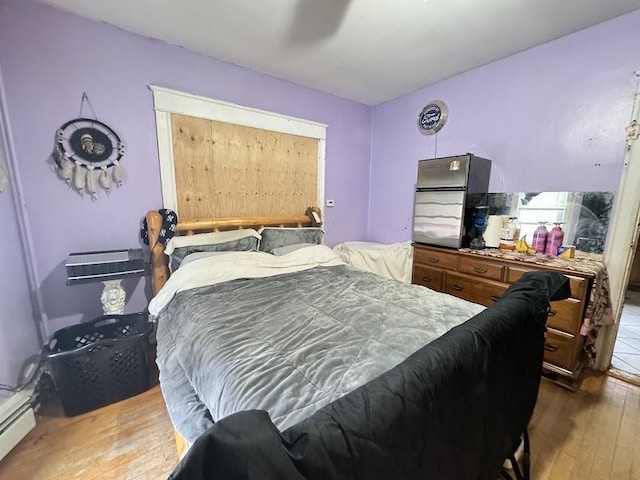 bedroom featuring baseboard heating and hardwood / wood-style floors