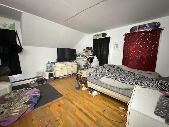 bedroom featuring vaulted ceiling, a baseboard heating unit, and wood finished floors