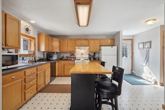kitchen featuring white appliances, light floors, baseboard heating, a kitchen bar, and a sink