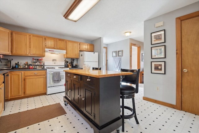 kitchen with light floors, under cabinet range hood, white appliances, and a kitchen bar