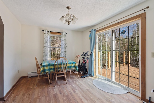 dining area featuring an inviting chandelier, baseboards, a textured ceiling, and wood finished floors