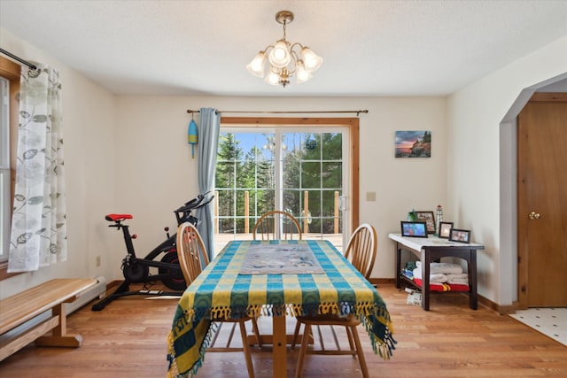dining area with arched walkways, baseboards, light wood-style flooring, and a chandelier