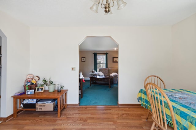dining area featuring arched walkways, baseboards, ceiling fan, and wood finished floors