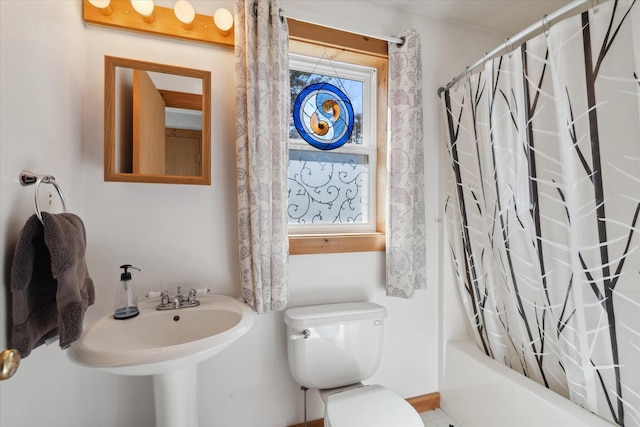 full bath featuring shower / bath combo with shower curtain, baseboards, and toilet