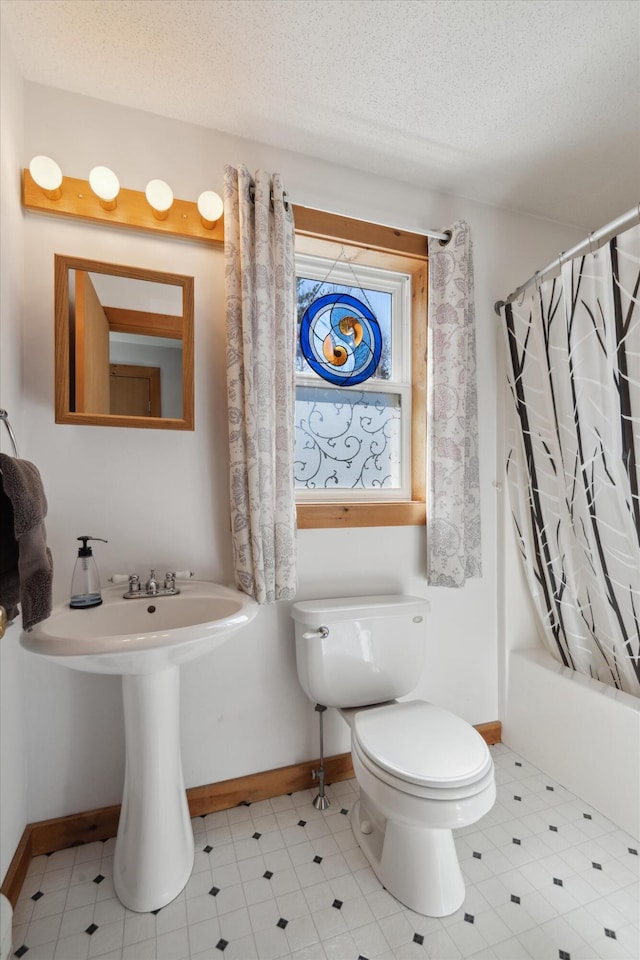 full bath with toilet, baseboards, shower / bathtub combination with curtain, and a textured ceiling