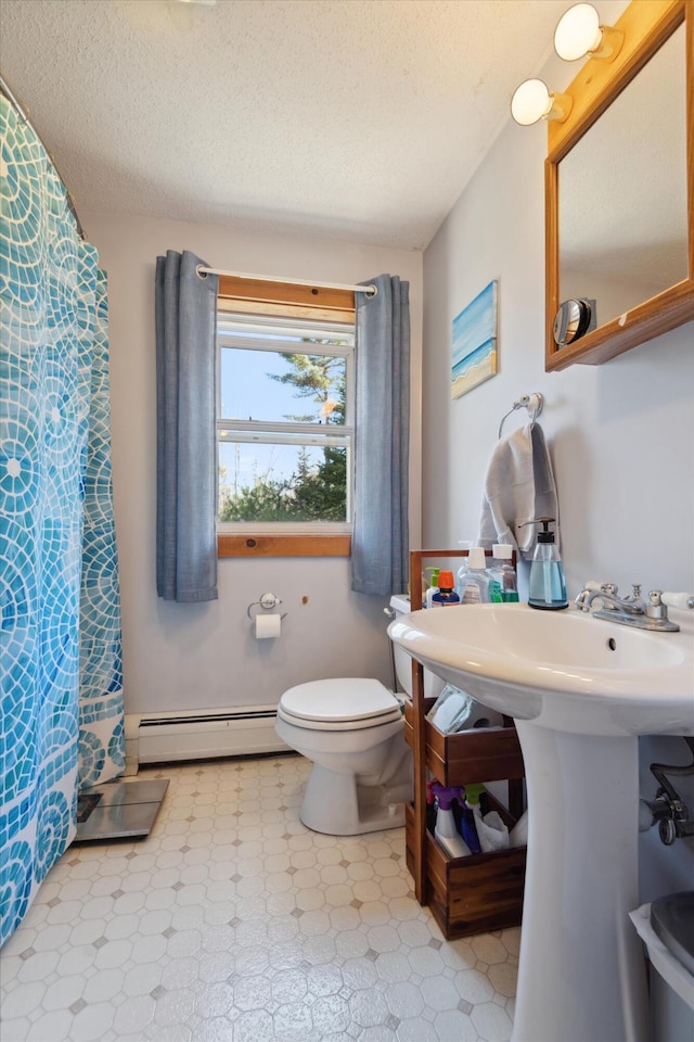 bathroom featuring tile patterned floors, a baseboard heating unit, toilet, and a textured ceiling