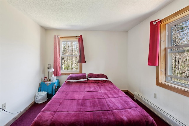 bedroom with carpet, baseboard heating, and a textured ceiling