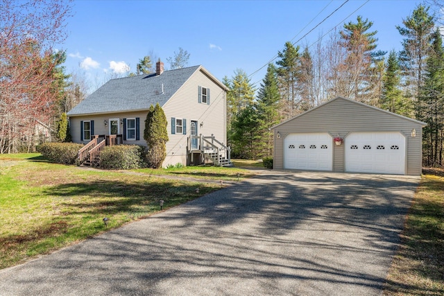 view of side of home featuring a shingled roof, a detached garage, an outbuilding, a chimney, and a yard