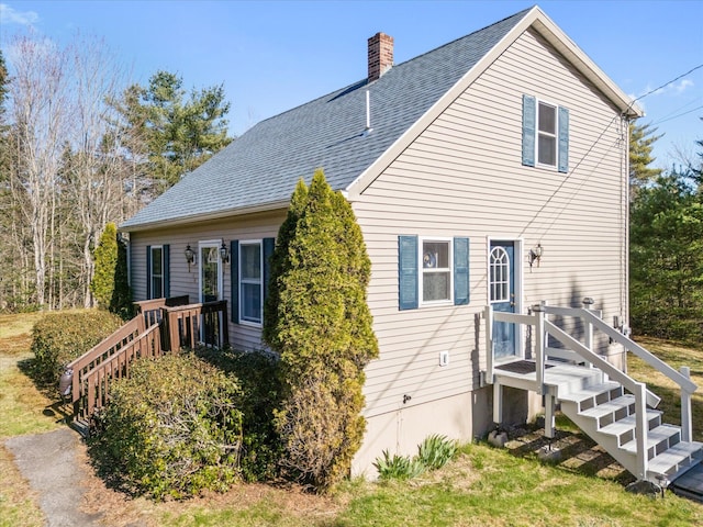 back of house featuring a shingled roof and a chimney