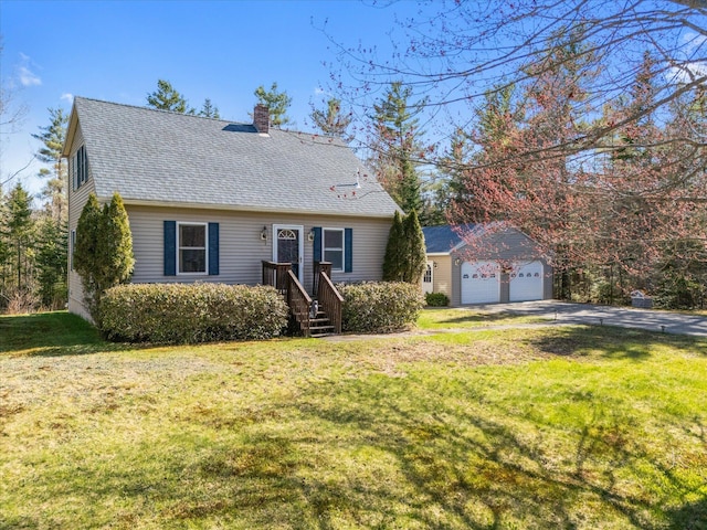 view of front of property with a front yard, a chimney, a shingled roof, concrete driveway, and an outbuilding