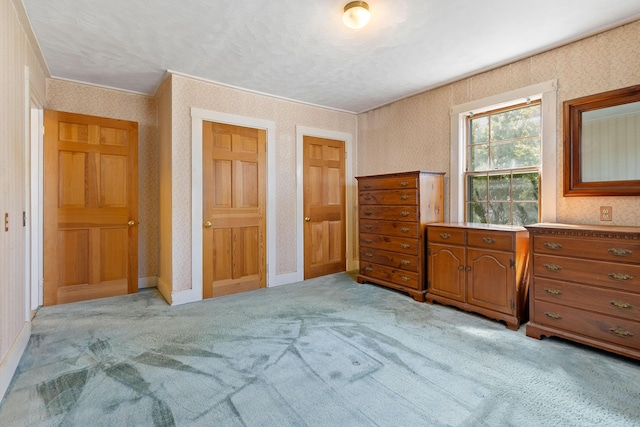 unfurnished bedroom featuring baseboards, light carpet, and wallpapered walls