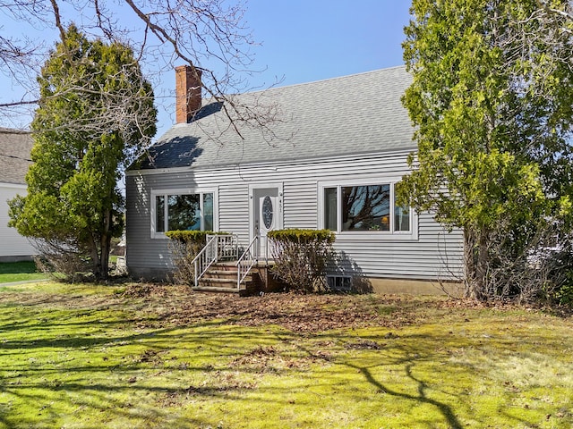 cape cod house featuring a front lawn, roof with shingles, and a chimney
