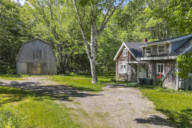 exterior space featuring a shingled roof, a chimney, an outbuilding, and a barn