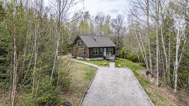 26 Mountain View Ln, Woodstock, ME 04219 - view of front of house with a wooded view, a wooden deck, a shingled roof, a front lawn, and log exterior
