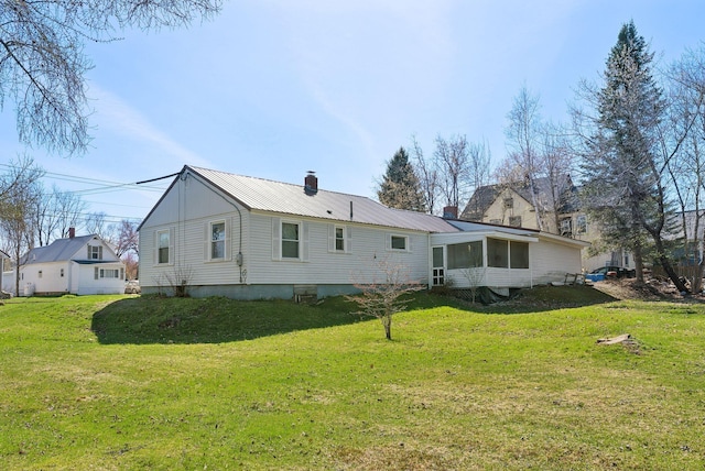 232 Peltoma Ave, Pittsfield, ME 04967 - back of house with a sunroom, a chimney, a yard, and metal roof