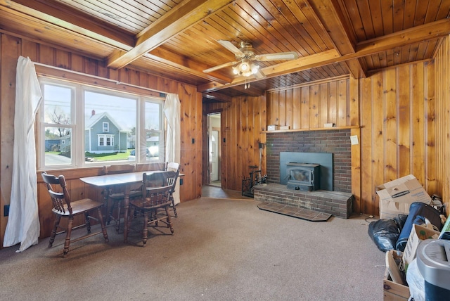 232 Peltoma Ave, Pittsfield, ME 04967 - carpeted living room featuring wooden ceiling, wood walls, beam ceiling, a wood stove, and ceiling fan