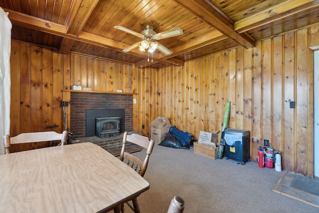232 Peltoma Ave, Pittsfield, ME 04967 - carpeted dining area featuring wooden ceiling, beam ceiling, a wood stove, wood walls, and a ceiling fan