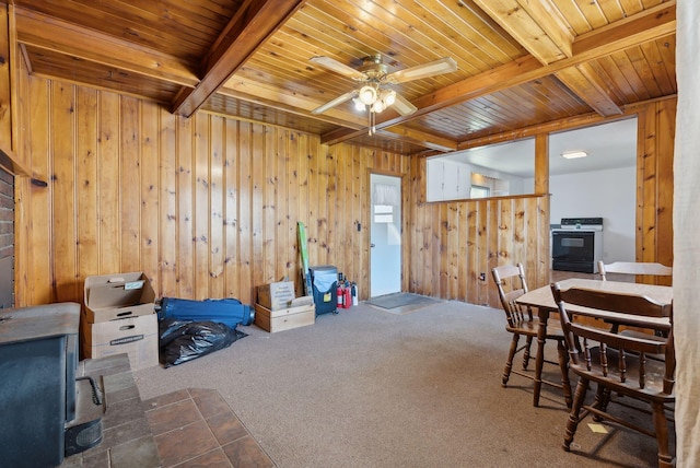 232 Peltoma Ave, Pittsfield, ME 04967 - carpeted dining space with wooden ceiling, beam ceiling, wooden walls, ceiling fan, and a wood stove