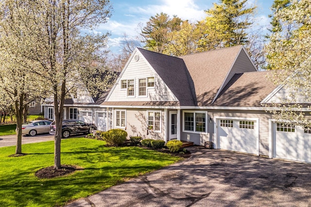 shingle-style home featuring an attached garage, roof with shingles, driveway, and a front yard