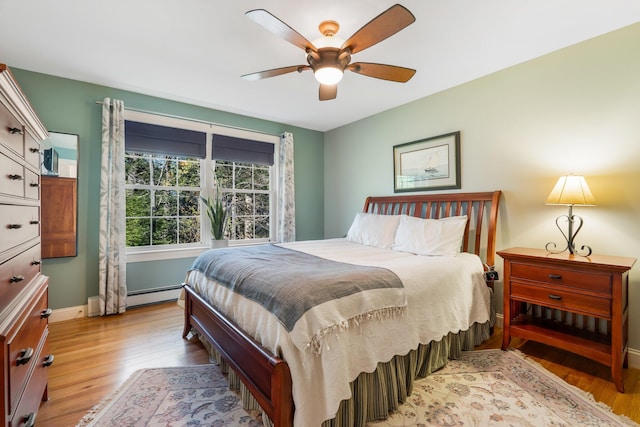 bedroom with light wood finished floors, a ceiling fan, baseboards, and a baseboard radiator
