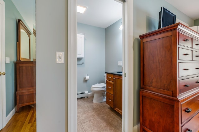 bathroom featuring a baseboard heating unit, baseboards, toilet, tile patterned floors, and vanity