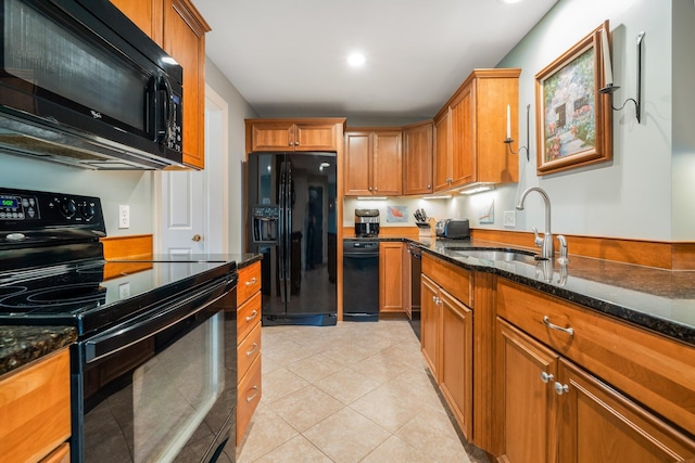 kitchen with a sink, black appliances, dark stone countertops, and brown cabinets