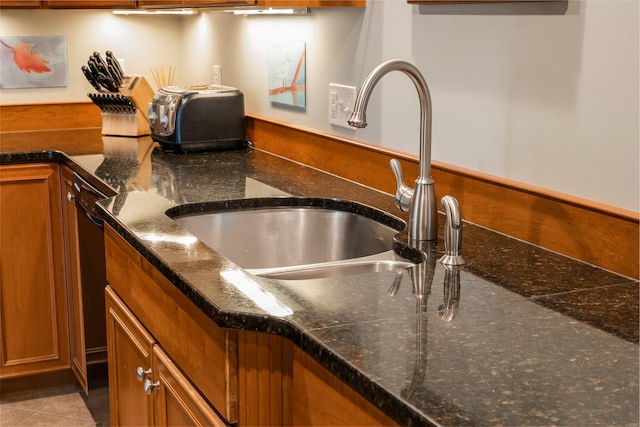 interior details with dark stone countertops, brown cabinetry, and a sink
