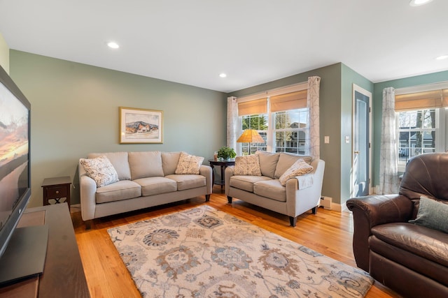 living room with light wood-type flooring, a baseboard radiator, and a healthy amount of sunlight